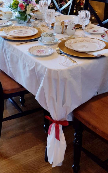 Vintage tablecloth with embroidery and tied back with colorful bow.
