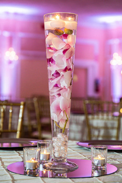 Pilsner Vase filled with orchids and floating candles Inside the Vase. Party Rentals by Royal Table Settings